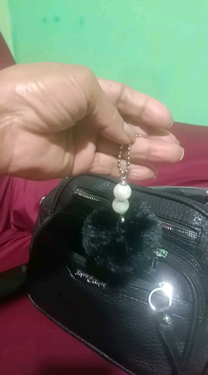 Detalhe do pingente da bolsa Amelise preta em avaliação